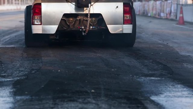 Drag racing car burns rubber off its tires in preparation for the race.