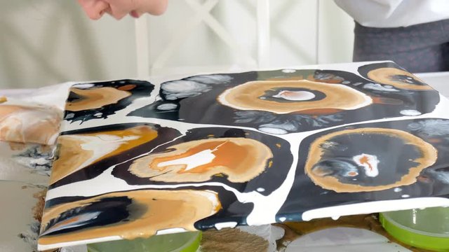 woman draws a picture of a fluid art on canvas