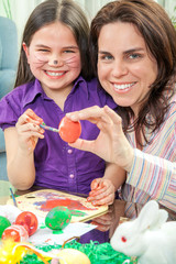 Mother and her children paint easter eggs