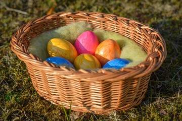 Several colorful Easter eggs in a basket on grass