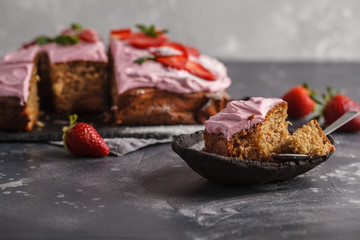 Piece of yogurt pound cake for breakfast with pink glaze and fresh strawberries. Dark background, summer berry dessert, copy space.