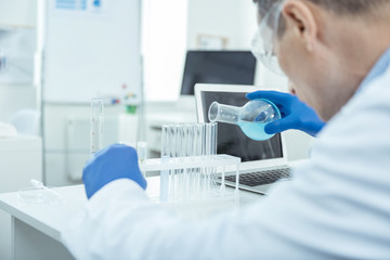 Lets discover. Experienced male researcher adding water to test tubes in a lab