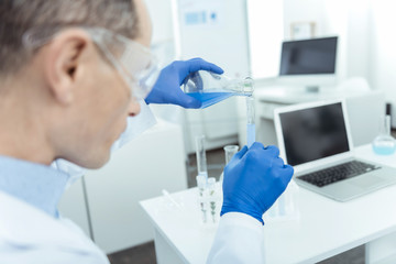 Add some liquid. Close up of test tube in hands of a professional scientist working in a lab
