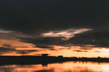 Fototapeta premium beautiful skyline with trees and buildings reflected in water at sunset, iceland
