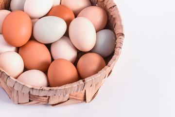 Colorful pastel eggs in a wicker basket on a white background. Concept-Easter, healthy food, organic products, farm products. Copy space.