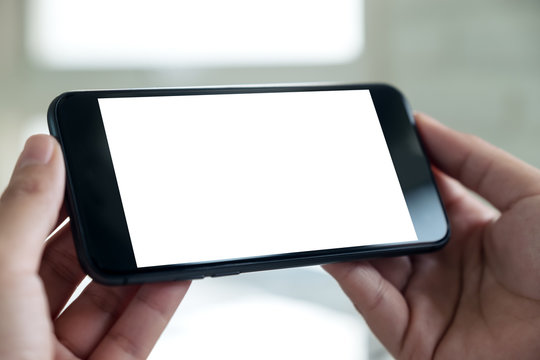 Mockup image of a hand holding black.mobile phone with blank white desktop screen
