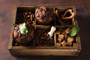 Chocolate muffins on a wooden box with grains of coffee and spices,