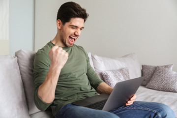 Excited young man using laptop