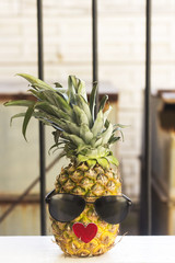 fresh pineapple fruit wearing sunglasses on wooden