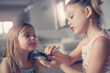 Cute little girls playing with make up in the room.