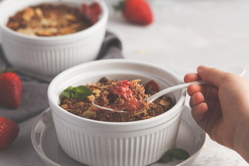 Summer breakfast strawberry crumble in child hand. Mini berry cake with strawberry, light background. Healthy vegan food concept.