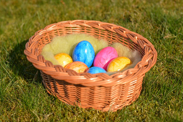 Several colorful Easter eggs in a basket on grass