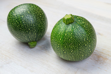 Two round zucchini on wooden background
