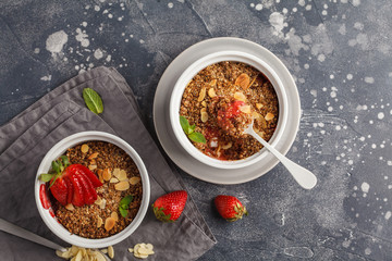Homemade breakfast strawberry crumble. Mini berry cake with strawberry, dark background, top view, copy space. Healthy vegan food concept.