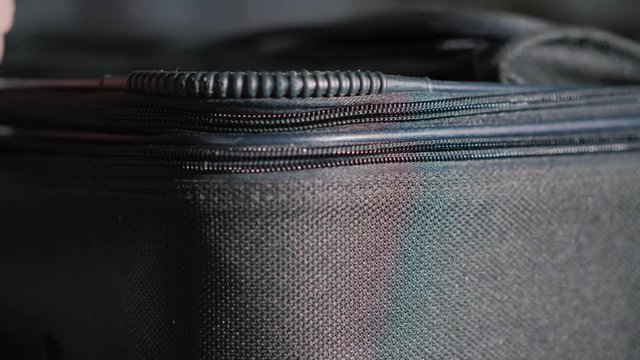 Travel and luggage concept: The man's hand opens and closes the zipper on the travel bag.