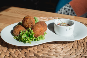 closeup of plate with spanish croquettes served with salad and sauce