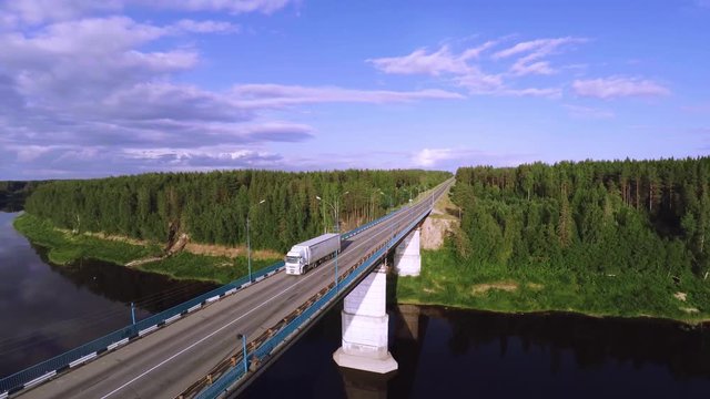 The truck driving over the bridge across the river, truck passes over the bridge, passes over the concrete bridge - Aerial view