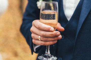 Married man holds glass of champagne in his arm