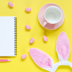 Easter holiday background with notebook and pen, cup for coffee, bunny ears and easter eggs
