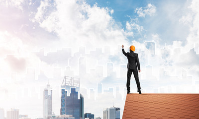 Man architect draw silhouette of modern city on blue sky. Mixed media