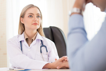 Female doctor holding patient hand at hospital. People with medical concept.