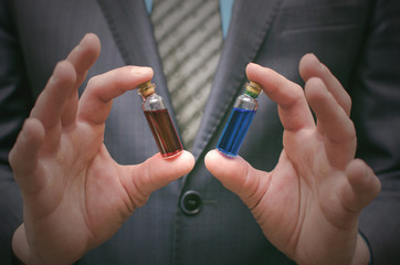 Blue and red pill essential liquid in business man hands. Choosing of right pill. Steroid or drug presentation. Medication for all diseases concept. Antibiotic pill comparison.