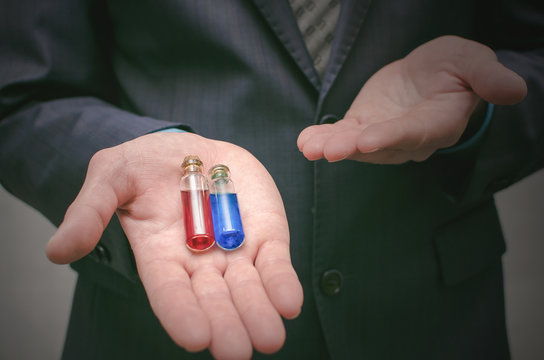 Blue And Red Pill Essential Liquid In Business Man Hands. Choosing Of Right Pill. Steroid Or Drug Presentation. Medication For All Diseases Concept. Antibiotic Pill Comparison.