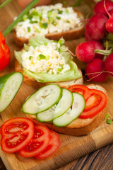 Summer sandwiches ingredients - cucumber, radish, tomato, mozzarella and eggs, white wood background, top view