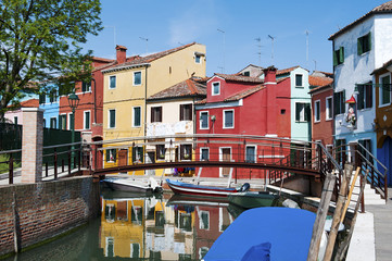 Fototapeta na wymiar Brightly colorful houses reflected in the canal in Burano, a beautiful island in the Venetian lagoon near Venice, Italy