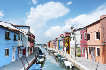 Fototapeta na wymiar Burano island, Italy - beautiful view of a street with colorful houses and canal. Venice postcard