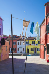 Fototapeta na wymiar Colorful facades with vibrant colors and laundry drying in famous fishermen village on the island of Burano, Venice, Italy