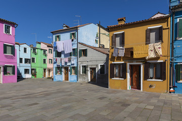 Fototapeta na wymiar Colorful buildings with vibrant colors and laundry drying in famous fishermen village on the island of Burano, Venice, Italy