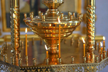 Church candle burns on the altar in front of the Orthodox icon