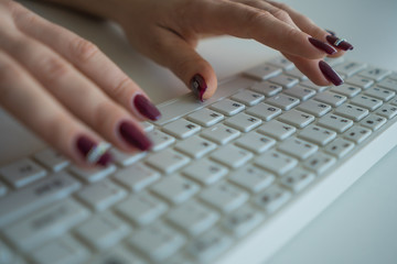 A woman is typing a message on a computer keyboard close-up
