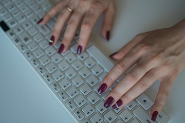 Top view of female hands with beautiful manicure on computer keyboard close-up