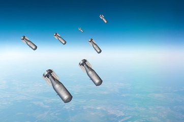 Falling bombs weapons charges dropped from a fighter combat aircraft high in the sky, a view of...