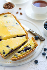 Tea time. Homemade blueberry cheesecake, cups of tea, nuts and berry on white table cloth