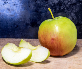 Green red apple and two pieces on a dark background