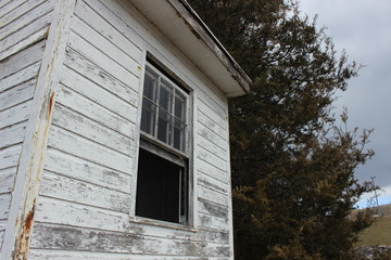 Open window in weathered white wooden building 