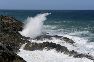 Hoch aufspritzende Gischt an einer  Felsenküste.