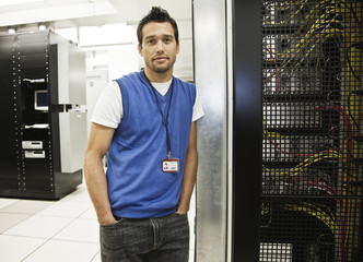 Portrait of a Caucasian male technician in a large server room.