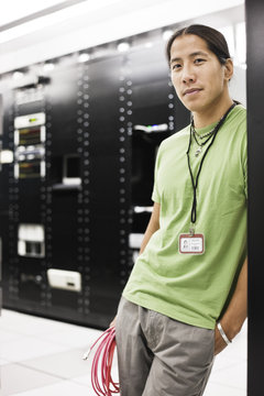 Portrait of an Asian American computer technician in a large computer server room