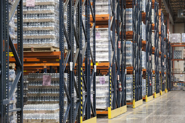 Interior of a warehouse showing flavoured bottled water stored on pallets and set on large racks.