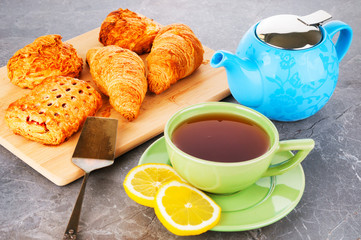 Breakfast on table with tea and fresh baked pastries