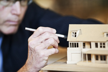 Caucasian male architect working on a scale model of a new home.