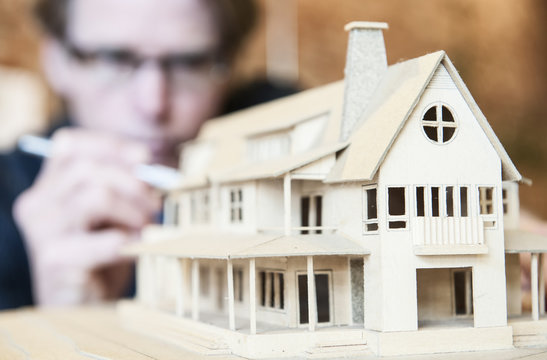 Caucasian male architect working on a scale model of a new home. - Powered by Adobe