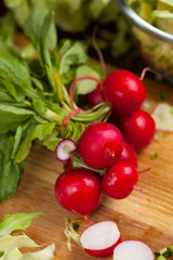 Fresh red radish in the beam with leaves on the old dark wooden background, selective focus