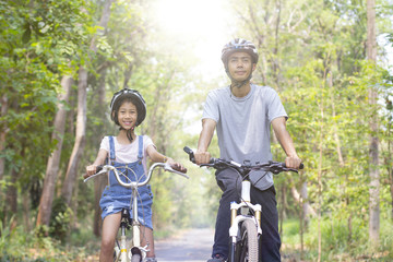 Fototapeta na wymiar Happy father and daughter cycling in the park, togetherness relaxation concept