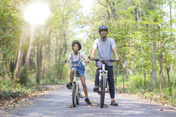 Happy father and daughter cycling in the park, togetherness relaxation concept