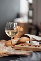 A glass of white wine and cheese on a blackboard